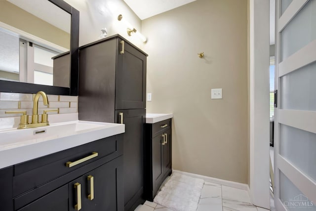bathroom featuring vanity, marble finish floors, tasteful backsplash, and baseboards