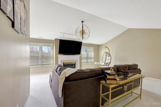 living room featuring carpet flooring, baseboards, plenty of natural light, a tiled fireplace, and a textured ceiling
