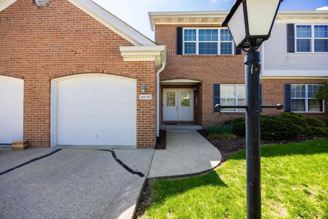 view of front of house featuring brick siding, concrete driveway, a front lawn, and a garage
