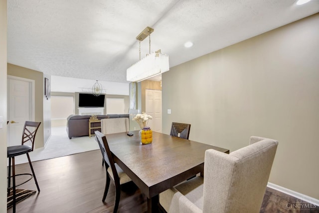 dining space featuring dark wood finished floors, a textured ceiling, baseboards, and recessed lighting