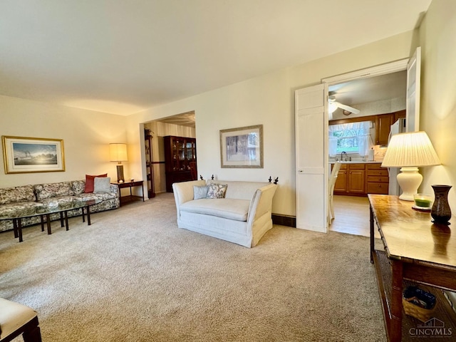 living area with light colored carpet and a ceiling fan