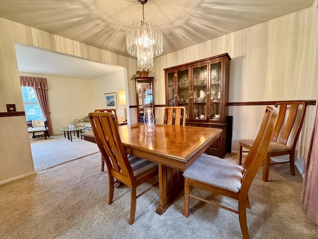 dining space featuring light colored carpet and a chandelier