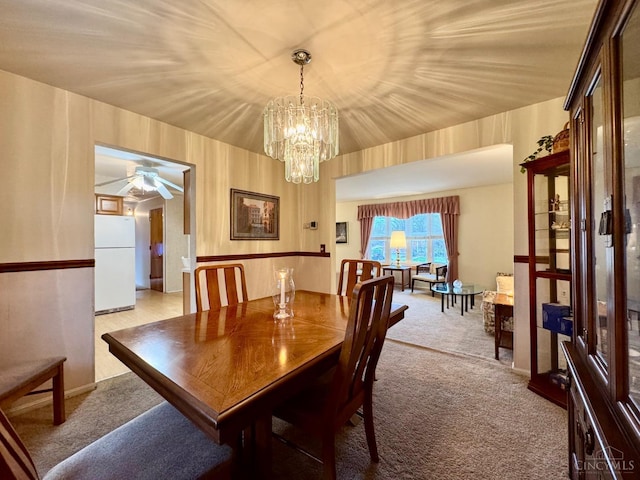 dining area featuring light colored carpet, ceiling fan, and a chandelier