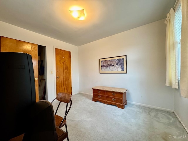 sitting room with light colored carpet, baseboards, and an office area