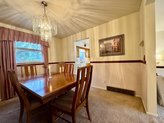 carpeted dining area featuring a chandelier and baseboards