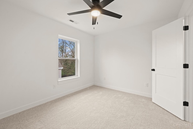 empty room with light colored carpet, a ceiling fan, and baseboards