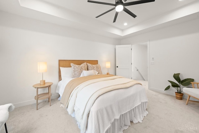 bedroom featuring light colored carpet, a tray ceiling, baseboards, recessed lighting, and a ceiling fan