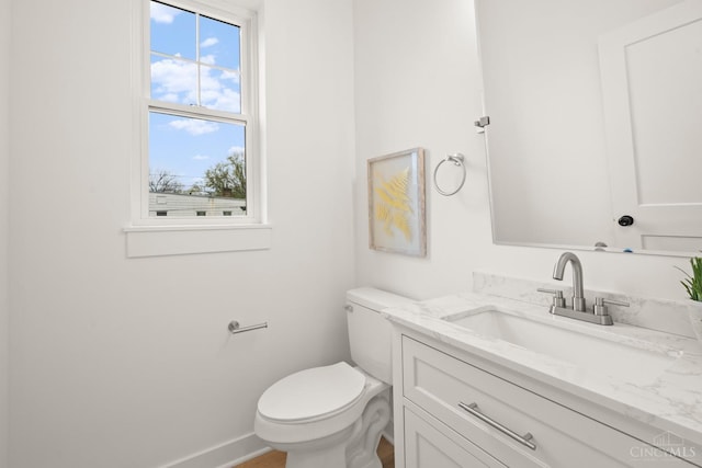 bathroom featuring plenty of natural light, toilet, vanity, and baseboards