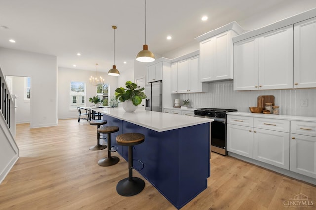 kitchen with appliances with stainless steel finishes, tasteful backsplash, a kitchen bar, a kitchen island, and light countertops