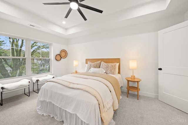 bedroom with light colored carpet, a raised ceiling, recessed lighting, baseboards, and ceiling fan