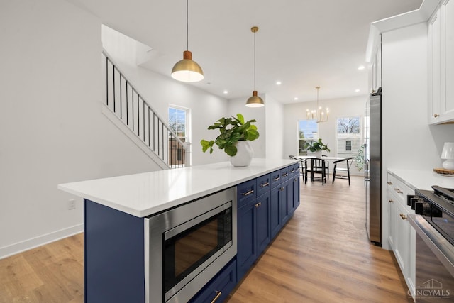 kitchen featuring blue cabinets, appliances with stainless steel finishes, white cabinetry, light countertops, and light wood-type flooring