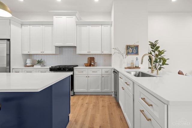 kitchen featuring stainless steel appliances, a sink, recessed lighting, a peninsula, and light countertops
