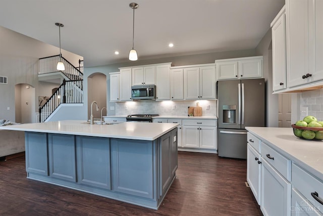 7690 Wharton Ct, West Chester, OH 45069 - kitchen with appliances with stainless steel finishes, arched walkways, decorative backsplash, dark wood-type flooring, and light countertops