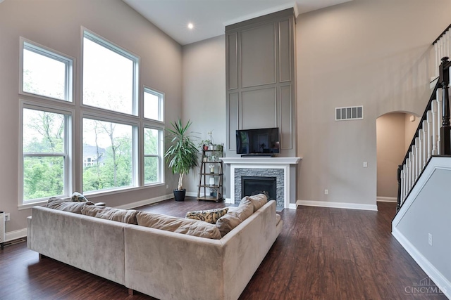 7690 Wharton Ct, West Chester, OH 45069 - living area with a high ceiling, arched walkways, dark wood-style floors, a stone fireplace, and stairs