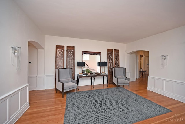 1 Beech Crest Ln, Cincinnati, OH 45206 - living area with arched walkways, a decorative wall, light wood-style floors, and wainscoting