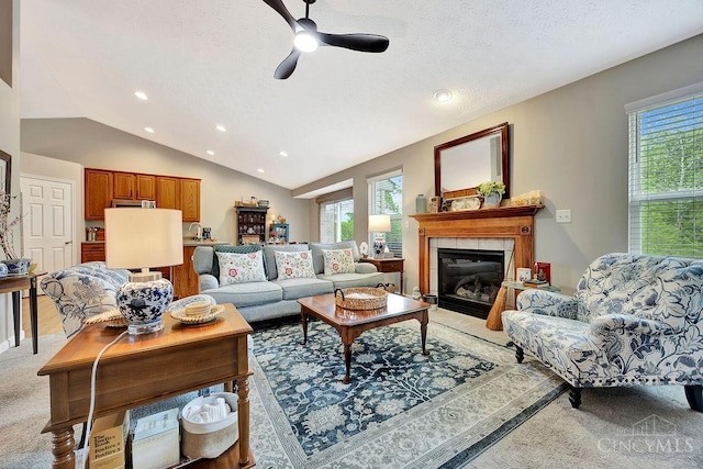 living area with lofted ceiling, plenty of natural light, recessed lighting, a ceiling fan, and a tile fireplace