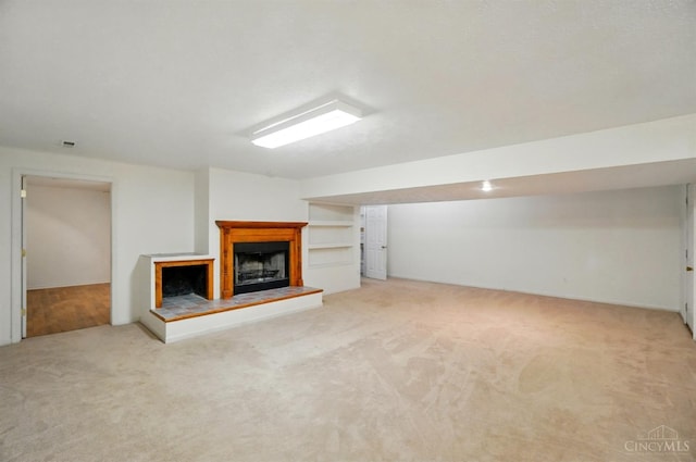 unfurnished living room with carpet flooring and a fireplace with raised hearth