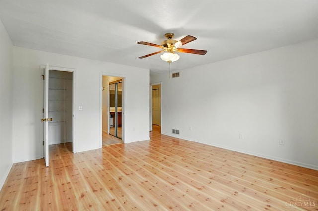 spare room featuring a ceiling fan, light wood finished floors, and baseboards