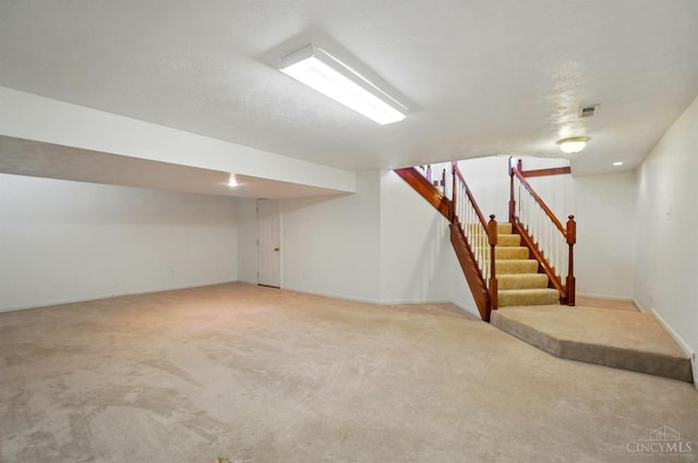 finished below grade area featuring light colored carpet, stairs, and baseboards