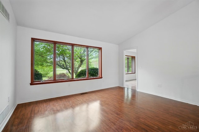 unfurnished room featuring lofted ceiling, wood finished floors, and baseboards