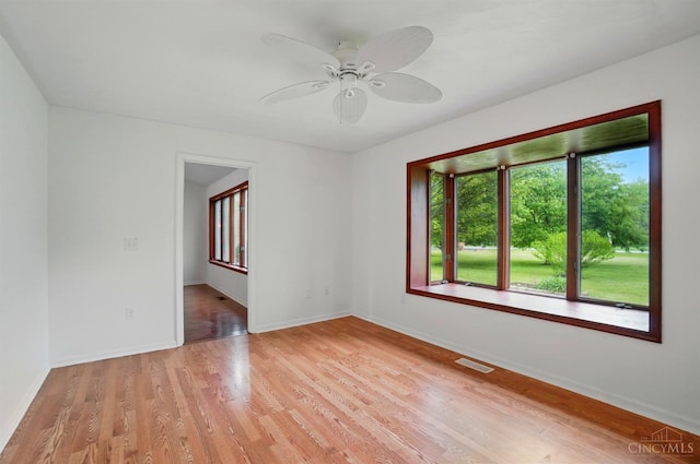 unfurnished room with ceiling fan, light wood finished floors, and baseboards