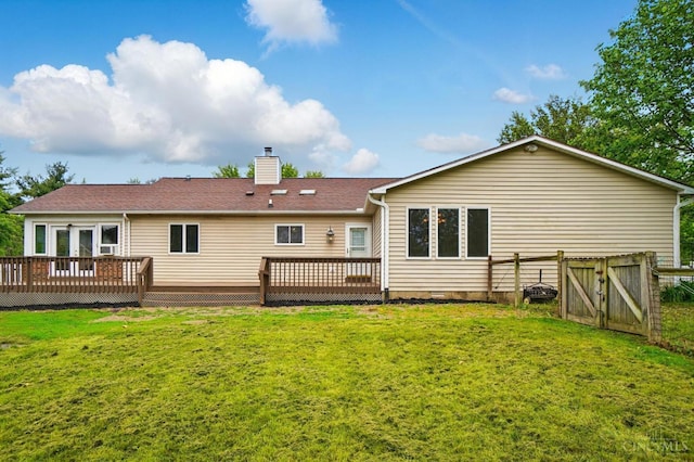 rear view of house featuring a deck, a chimney, and a gate