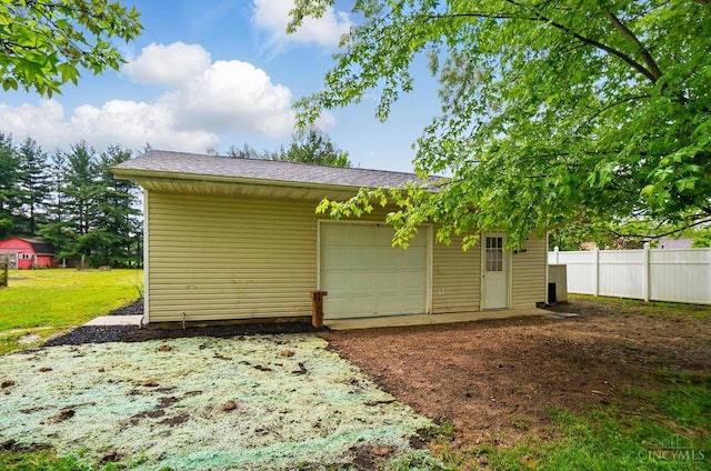 garage with fence and dirt driveway