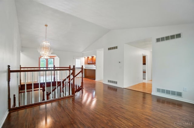 spare room with a chandelier, wood finished floors, baseboards, and high vaulted ceiling
