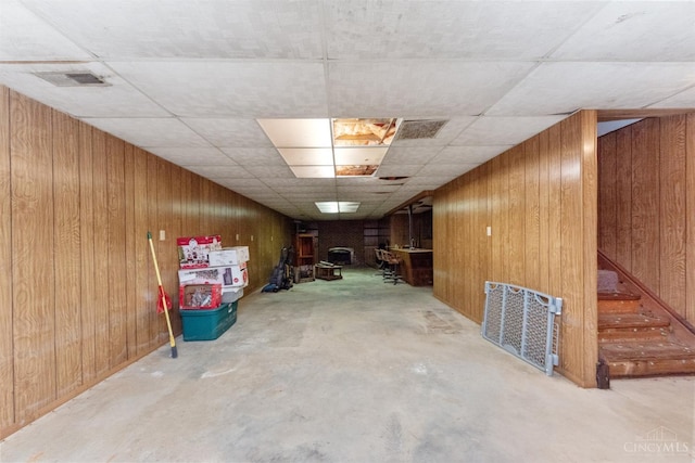 finished below grade area featuring wooden walls and a drop ceiling