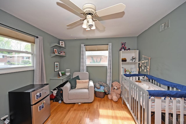 5638 Victoryview Ln, Delhi Twp, OH 45233 - bedroom featuring a crib, multiple windows, light wood-type flooring, and a ceiling fan