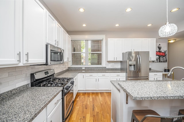 709 E Mcmillan St Unit 1, Cincinnati, OH 45206 - kitchen featuring stainless steel appliances, white cabinetry, light wood finished floors, decorative backsplash, and recessed lighting