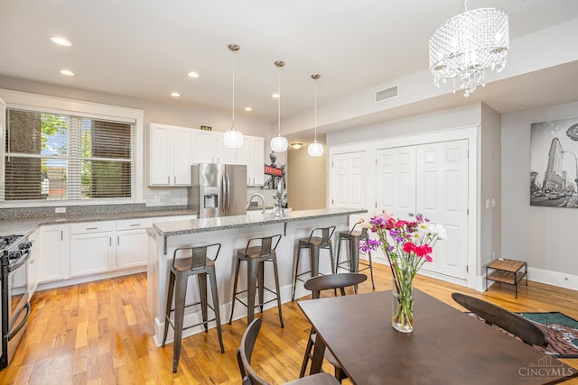 709 E Mcmillan St Unit 1, Cincinnati, OH 45206 - kitchen with appliances with stainless steel finishes, a breakfast bar area, white cabinetry, recessed lighting, and light stone counters
