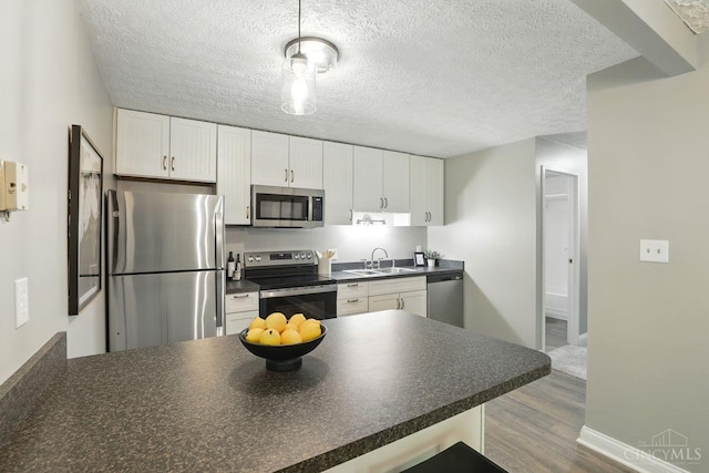 6607 Hearne Rd Unit 90, Green Twp, OH 45248 - kitchen with stainless steel appliances, dark countertops, wood finished floors, a sink, and white cabinets