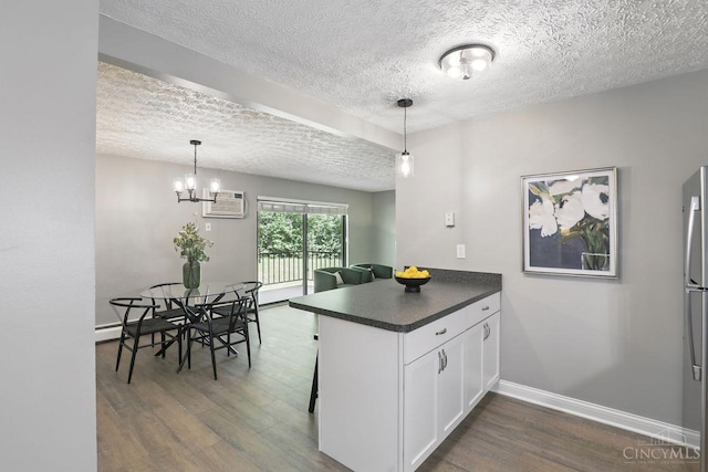 6607 Hearne Rd Unit 90, Green Twp, OH 45248 - kitchen with dark wood-style floors, dark countertops, a textured ceiling, white cabinets, and a peninsula