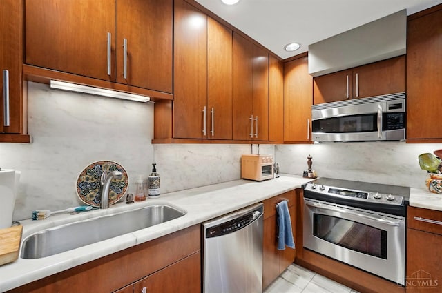 1617 E Mcmillan St Unit 605, Cincinnati, OH 45206 - kitchen featuring appliances with stainless steel finishes, tasteful backsplash, light countertops, brown cabinets, and recessed lighting