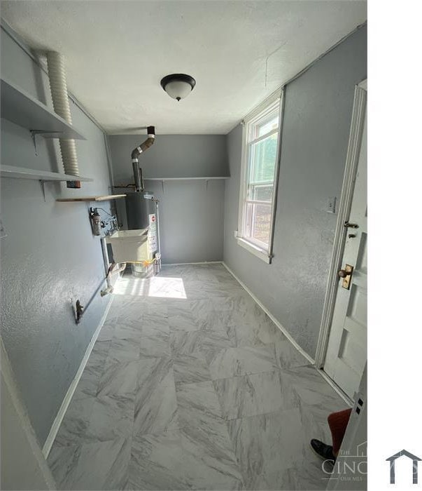 2196 Champlain St, Cincinnati, OH 45214 - clothes washing area with baseboards, water heater, and marble look tiles