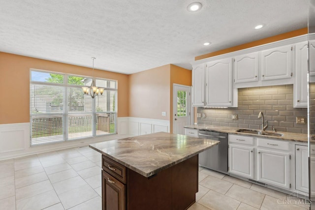5 Artesian Ct, Springboro, OH 45066 - kitchen with stainless steel dishwasher, a sink, a wainscoted wall, a decorative wall, and light stone counters