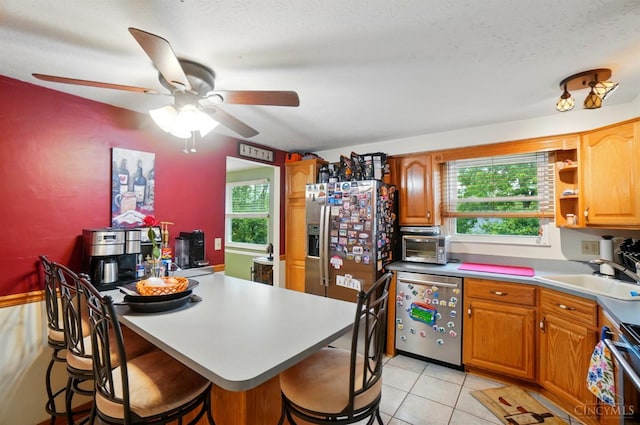 12056 Hazelhurst Ln, Springfield Twp, OH 45240 - kitchen featuring a sink, stainless steel appliances, a breakfast bar area, ceiling fan, and light tile patterned floors