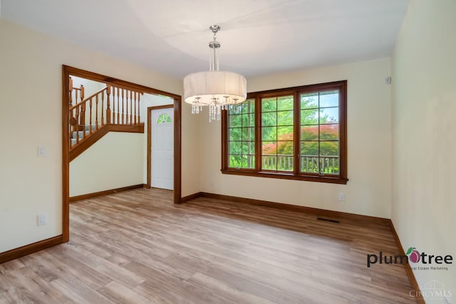 378 Natalie Ln, Turtle Creek Twp, OH 45036 - empty room featuring wood finished floors, a chandelier, baseboards, and stairs