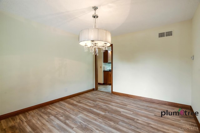 378 Natalie Ln, Turtle Creek Twp, OH 45036 - unfurnished room with light wood-style flooring, a chandelier, and baseboards