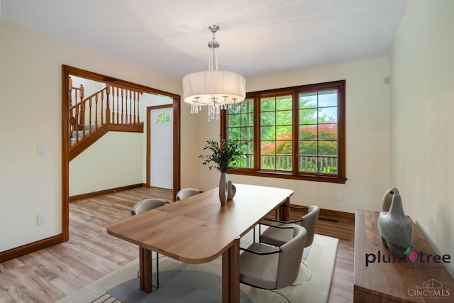 378 Natalie Ln, Turtle Creek Twp, OH 45036 - dining room with wood finished floors, baseboards, stairs, and a chandelier