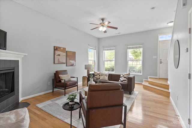 1441 Laurel Park Dr, Cincinnati, OH 45214 - living area featuring light wood-style flooring, a ceiling fan, a tiled fireplace, and baseboards