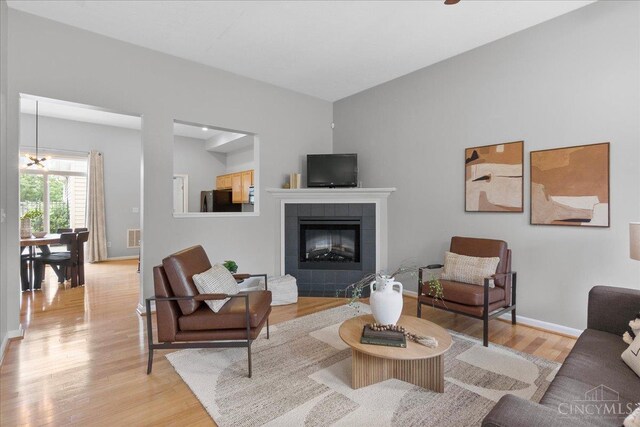 1441 Laurel Park Dr, Cincinnati, OH 45214 - living room featuring light wood-style flooring, baseboards, a fireplace, and a chandelier