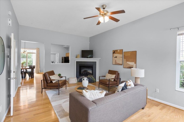1441 Laurel Park Dr, Cincinnati, OH 45214 - living room with light wood finished floors, a ceiling fan, vaulted ceiling, baseboards, and a tiled fireplace