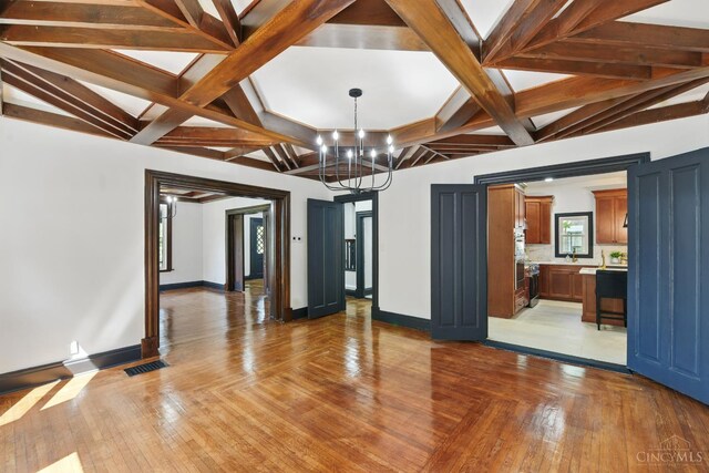 752 S Fred Shuttlesworth Cir, Cincinnati, OH 45229 - unfurnished living room featuring a chandelier, baseboards, light wood-style floors, beam ceiling, and coffered ceiling
