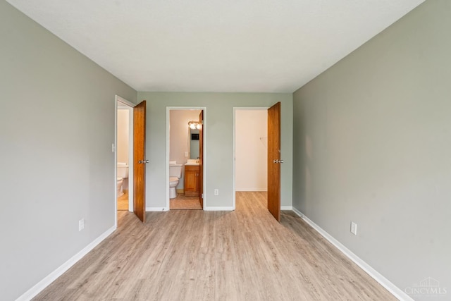 6644 Hearne Rd Unit 202, Green Twp, OH 45248 - unfurnished bedroom featuring light wood-style flooring, baseboards, a spacious closet, ensuite bathroom, and a closet