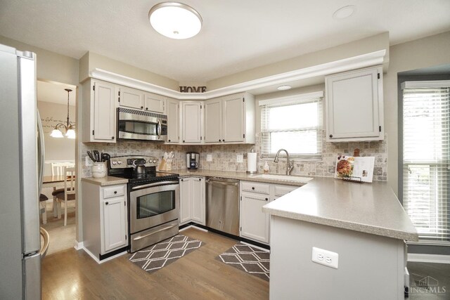 5509 Windmere Dr, Green Twp, OH 45248 - kitchen with appliances with stainless steel finishes, a sink, a peninsula, backsplash, and dark wood finished floors