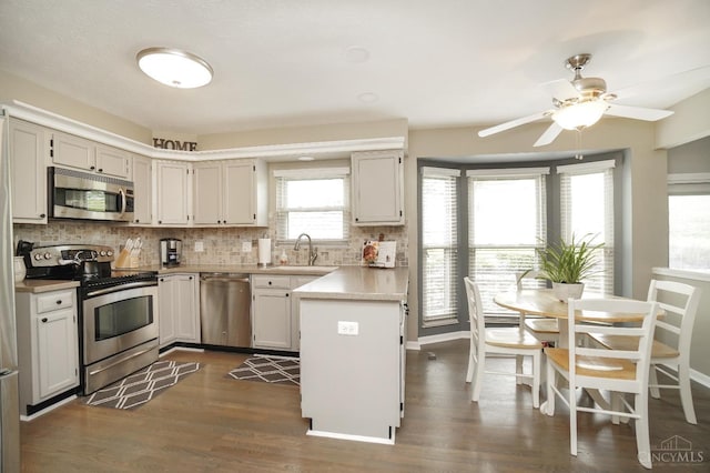 5509 Windmere Dr, Green Twp, OH 45248 - kitchen with appliances with stainless steel finishes, a peninsula, decorative backsplash, dark wood-type flooring, and light countertops