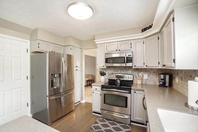 5509 Windmere Dr, Green Twp, OH 45248 - kitchen with stainless steel appliances, light countertops, decorative backsplash, dark wood finished floors, and white cabinetry