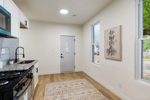 926 Shuler Ave, Hamilton, OH 45011 - kitchen with light wood-style flooring, a sink, white cabinets, decorative backsplash, and black range with gas cooktop